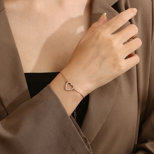 Détail du bracelet cœur en or rose avec diamants micro-pave portés sur le poignet
