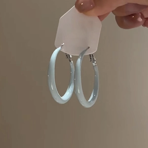 Close-up of light blue resin hoop earrings with a glossy finish on white card