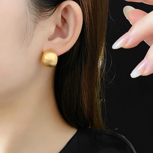 Nahaufnahme goldener runder Ohrstecker mit gebürsteter Textur am Ohr des Modells