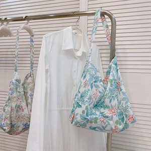 Detalle de bolsas de algodón con estampado floral colgadas en un perchero con un vestido.