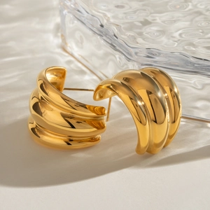 Boucles d'oreilles créoles C en acier inoxydable doré 18 carats sur fond de verre d'eau