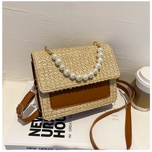 Detailed shot of straw woven crossbody bag with pearl handle and brown leather trim