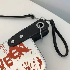 Detail of creative cleaver bag with bloody print, metal rings, and black leather strap