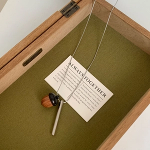 Vue macro d'un collier pendentif gland en bois dans son écrin de velours vert olive