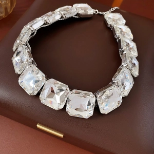 Primo piano di una collana d'argento con grandi cristalli quadrati su un portagioie in pelle