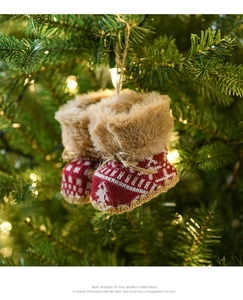 Detail of red knit Christmas boot ornaments with faux fur trim hanging on a festive tree