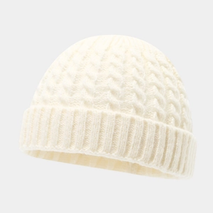 Macro detail of the creamy white cable knit texture and ribbed brim of the beanie cap
