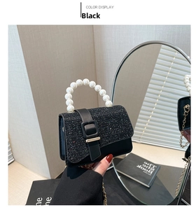 Detail of a black mini square bag with glitter flap and white pearl top handle