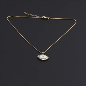 Gold evil eye necklace with blue zircon pendant and clear crystals on dark grey background