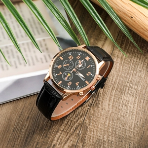 Close-up of a men's business watch with black leather strap and rose gold case on wood