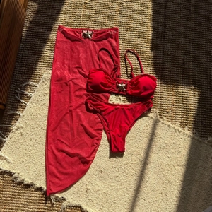 Set bikini rosso con gonna in rete e fibbie a stella dorate su tappeto intrecciato
