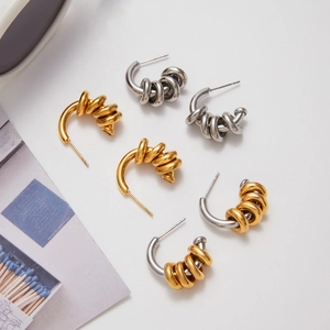 Flat lay of luxury C-shaped stainless steel earrings in gold, silver, and mixed tones