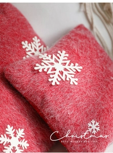 Close-up of red felt Christmas pillow with 3D white snowflakes and artistic lettering