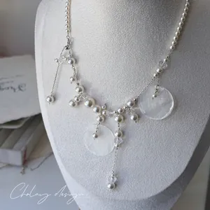 Detail view of multilayer pearl necklace with crystal beads and white shell pendants