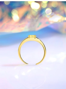 Macro detail of adjustable gold silver ring with a prong-set yellow gem and bokeh background