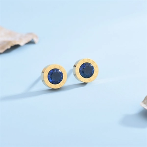 Macro shot of gold Roman numeral stud earrings with faceted navy blue center stones