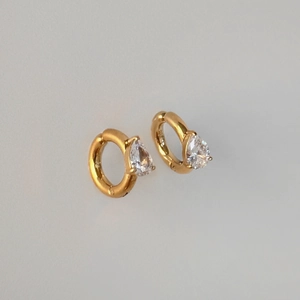 Close-up of gold-plated hoop earrings with sparkling pear-cut zircon stone settings