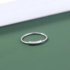 Macro shot of silver U-shaped stainless steel nose ring with smooth rectangular detail