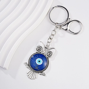 Detail of owl keychain with evil eye charm, blue tree pattern, and lobster clasp