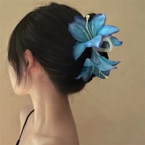 Detail of blue lily fabric flower hair claw clip on elegant updo hairstyle for women