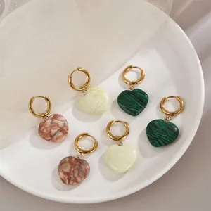 Heart-shaped natural stone earrings set in gold finish on a white ceramic plate