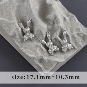 Detalle de tres colgantes de conejo plateados con circonita sobre piedra gris