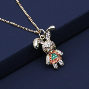 Macro view of gold rabbit pendant with multi-colored gemstones on blue leather