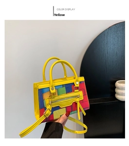 Detail of yellow shoulder bag featuring multi-color geometric block pattern and zipper pocket