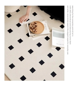 Detail of woven floor mat with black and white stone pattern in a cozy home setting