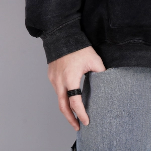 Detail of men's wide black ring with woven texture worn in a casual lifestyle setting