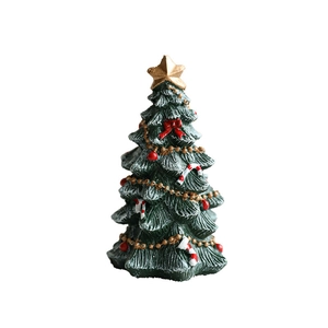 Mini green resin Christmas tree with gold star, red bows, and white snow on a white background