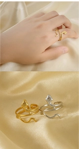 Detail of snake-shaped rings in gold and silver finish with textured scales on silk