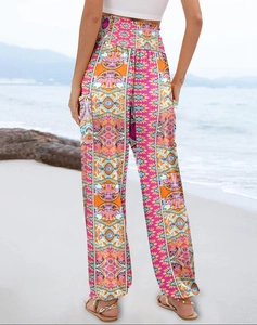 Detail of high waisted bohemian wide leg trousers with vibrant ethnic print on beach
