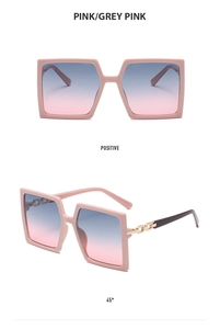 Close-up of pink oversized square sunglasses with gradient lenses and chain temple detail