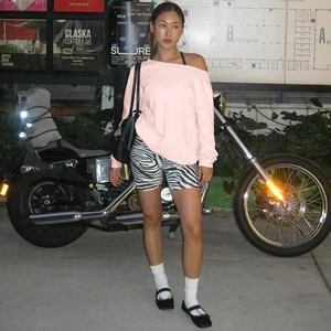 Street style detail of a pink off-shoulder long sleeve top paired with zebra shorts