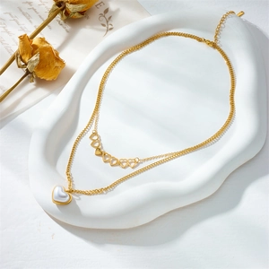 Double-layered gold pearl necklace with hollow heart charms on a white display tray