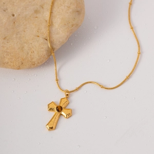 Vue détaillée du pendentif croix dorée avec texture martelée et pierre œil de tigre