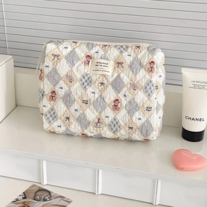 Detailed shot of a quilted cosmetic bag with teddy bear patterns and a stylish cloth label