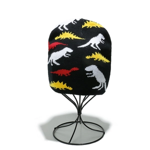 Detailed macro view of the knitted black beanie texture with colorful dinosaur patterns