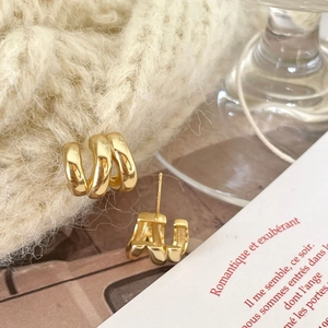 Detail of 925 sterling silver gold wavy earrings on elegant beige knitted fabric