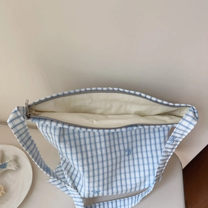 Macro detail of blue checkered cotton tote bag showing zipper closure and soft lining