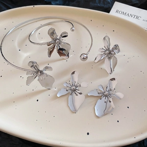Detail view of silver floral metal cuff bracelet and matching earrings on ceramic tray
