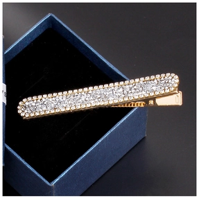 Detail of a rectangular gold-plated hair clip featuring rows of sparkling white rhinestones