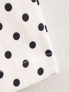 Gros plan détaillé du motif à pois noirs et des coutures précises sur le pantalon blanc
