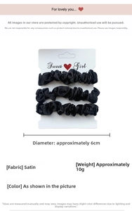 Detailed view of three black satin scrunchies displayed on a white product card