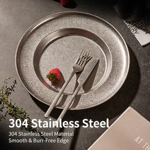 Deep stainless steel snowflake pasta plate with cutlery on a dark stone surface