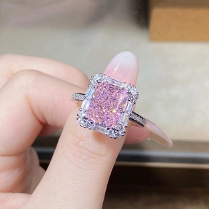 Close-up of a pink emerald-cut zircon ring with a halo of small diamonds on a silver band