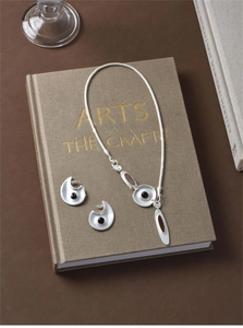 Detailed macro view of S925 silver irregular pendant and stud earrings set on a book