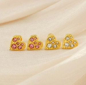 Close-up of heart-shaped 18K gold earrings with pink and clear crystals on silk