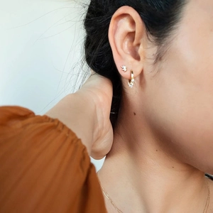 Close-up of gold stud earrings with marquise crystals worn on ear for a minimalist look